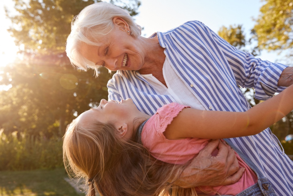 A grandmother playing with her granddaughter outside.