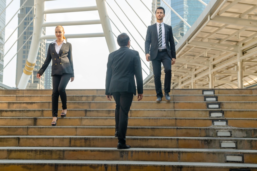 Three office workers crossing on some steps.