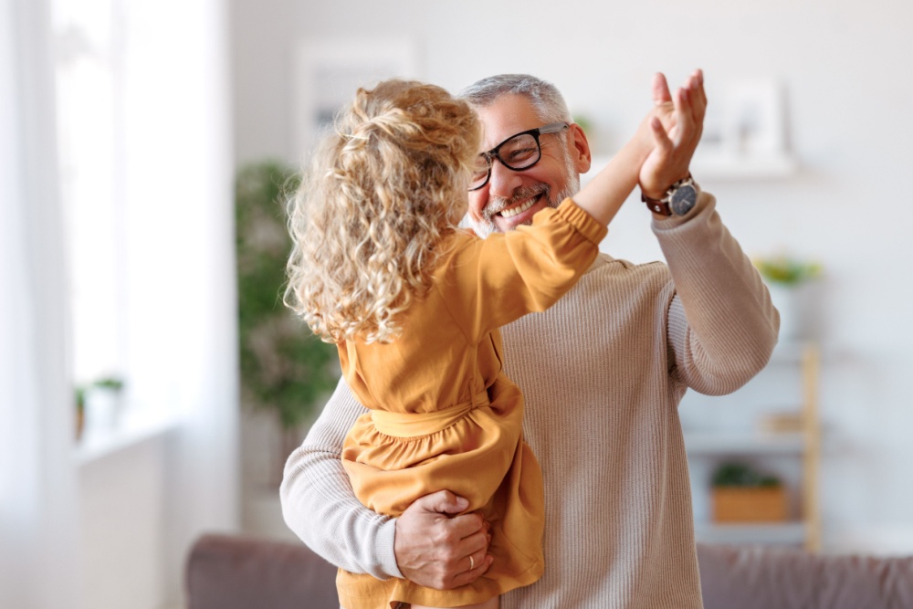 A grandfather playing with his granddaughter at home.